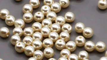 Pearl beads scattered on gray surface.