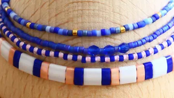 Stacked colorful bead bracelets on wrist.