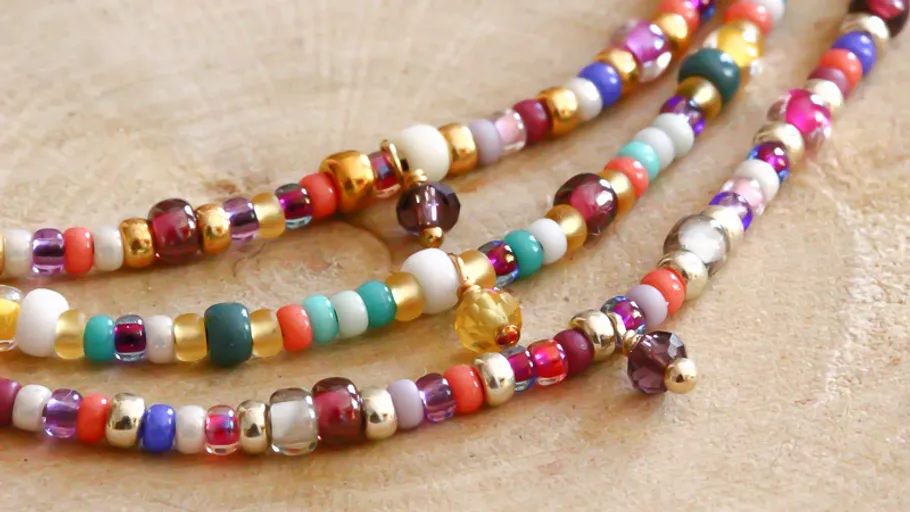 Colorful beaded necklaces on wooden surface.
