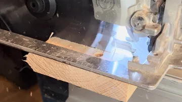 Circular saw cutting wooden plank, close-up view.