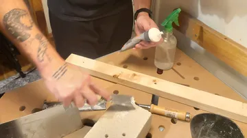 Person applying putty on a brick, workbench setting.