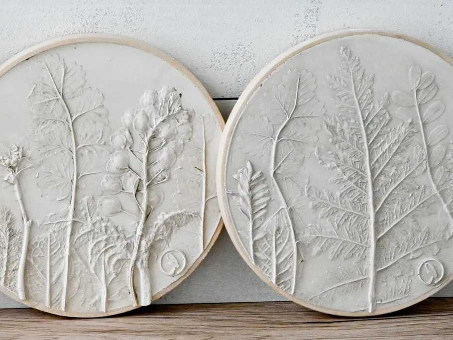 Round reliefs with plant motifs on a light grey background.