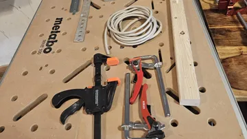 Workbench with clamps, ruler, and cable.