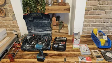 Tools on wooden table, shelves behind.