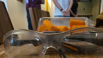 Safety goggles in front of carrot slices on table.