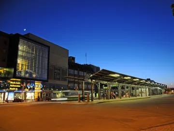 Bahnhof mit beleuchtetem Wartebereich bei Nacht.