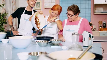 Drei Personen kochen gemeinsam in einer hellen Küche.