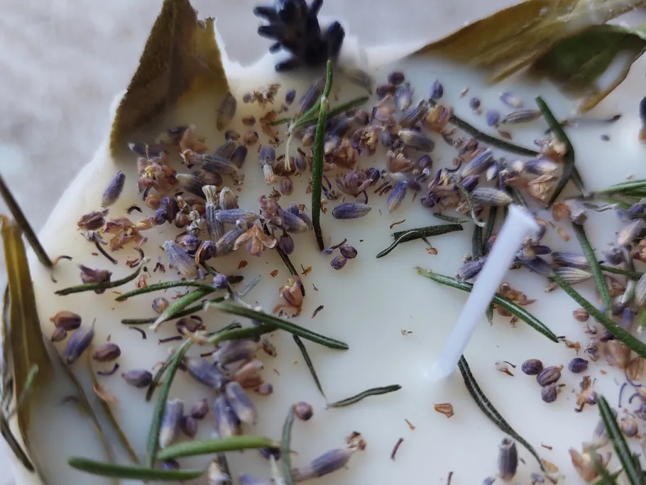 Eine Kerze mit Lavendel und Rosmarin in Wachs.