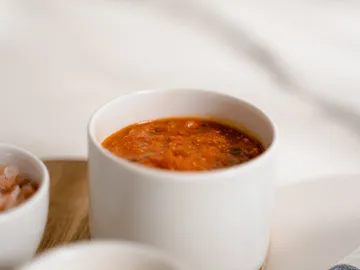 Eine Schüssel mit roter Soße auf einem Tisch.