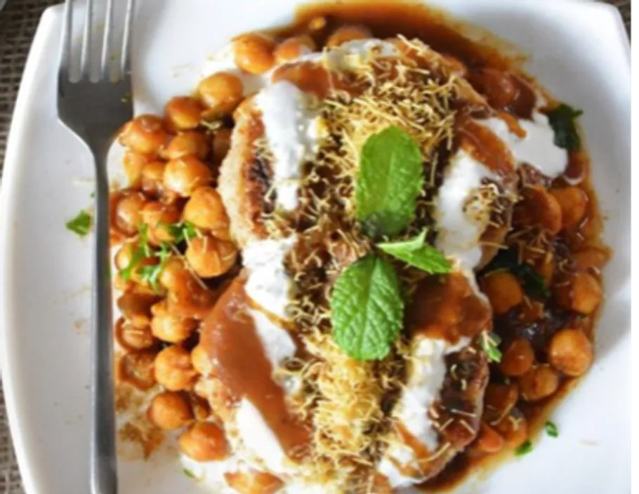 Plate with chickpeas, yoghurt, sauce and spices.