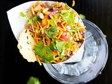 Paper cup contains colorful, mixed ingredients and herbs.