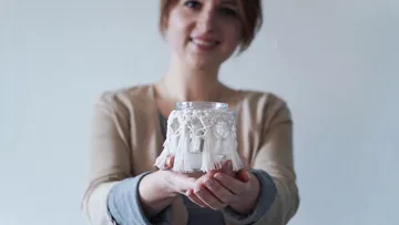 Woman holding a decorative glass jar with fringes.