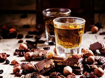Chocolates and glasses surrounded by nuts and dried fruits.