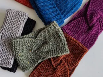 Bunte Strickkopfbedeckungen liegen auf einem weißen Tisch.