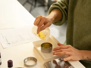 A person pours oil into a round can.