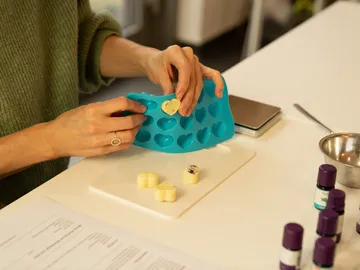 A hand removes shapes from a heart-shaped silicone mold.