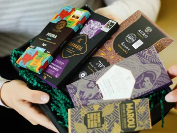 Sechs Schokoladentafeln in einer Geschenkbox werden gehalten.