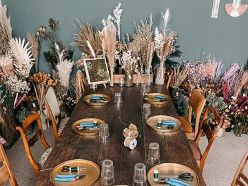 Ein gedeckter Tisch mit Werkzeugen, umgeben von Trockenblumen.