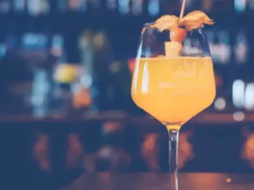 A cocktail glass with an orange drink is on a table.