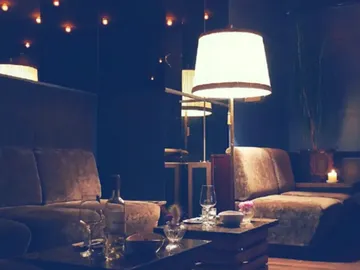Gemütliche Sitzecke mit Lampe und Getränken, gedämpftes Licht.