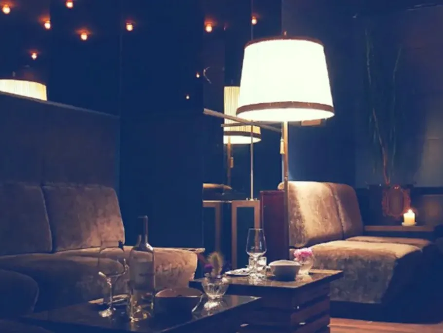 Gemütliche Sitzecke mit Lampe und Getränken, gedämpftes Licht.