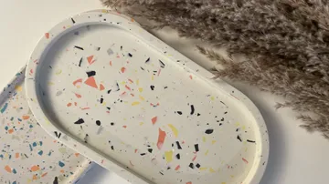 Colored plate is lying on a table with plants.