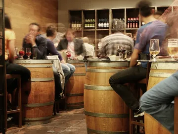 Wooden barrels as tables, people eat and drink in them.