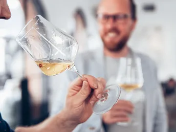 Glass is waved while laughing men stand in the background.