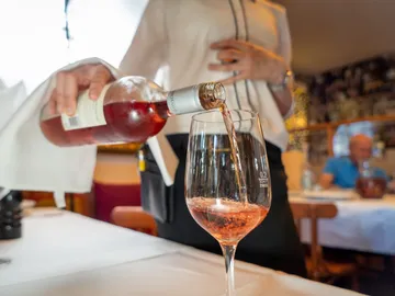 A person pours rosé wine into a glass.