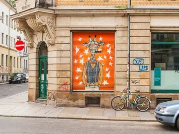 Giraffen-Mural an Wand, Straße mit Fahrrad und Autos.