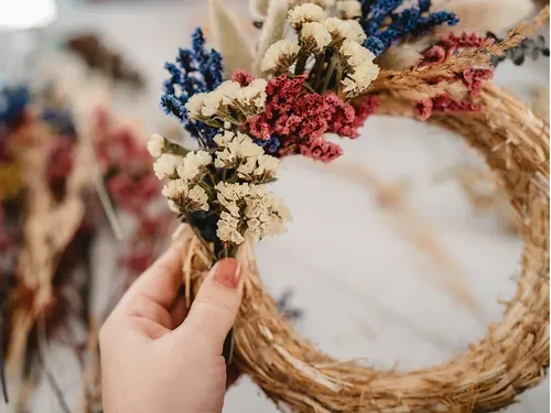 Hand holding a blooming wreath of dried flowers.