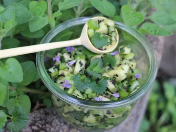 Grüner Salat in einer Schüssel mit Löffel und Kräutern.
