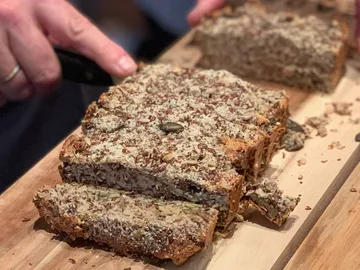 Schnelles Brot wird in Scheiben auf einem Holzbrett geschnitten.