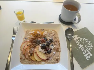 Schüssel mit Müsli, Obst und Getränken auf Tisch.