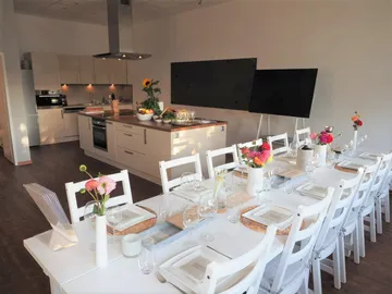 Eleganter Esstisch, gedeckt in modernem Küchenraum mit Blumen.
