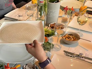 One hand holds a plate of rice paper at the table.