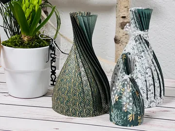 Three decorative paper vases are placed on a table.
