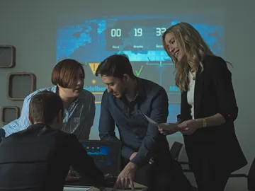 Four people are discussing at a table in a conference room.