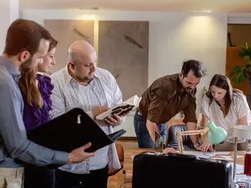 Five people work together at a table.