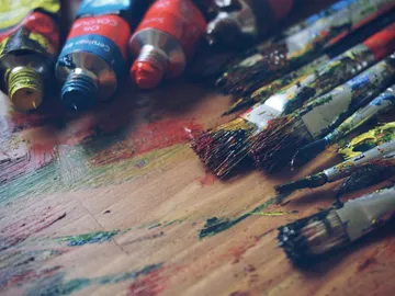 Tubes of paint and brushes lie on a painted table.