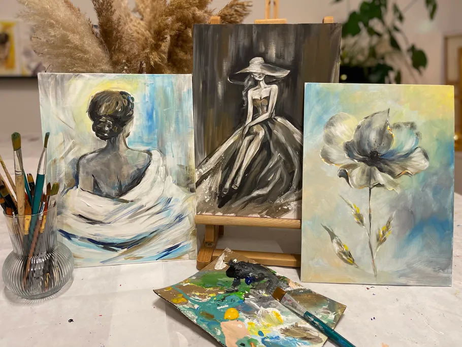 Three gem paintings stand on a table; brush next to them.