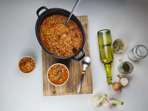 Stew in a pot served on a wooden board.