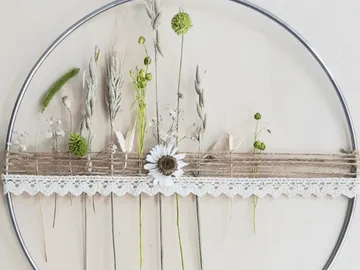 Circular frame decorated with dried flowers on the wall