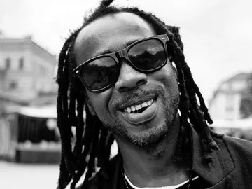 Smiling man wearing sunglasses standing outdoors.