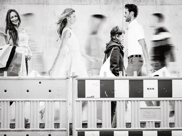 Women and men walk on the street with shopping bags.