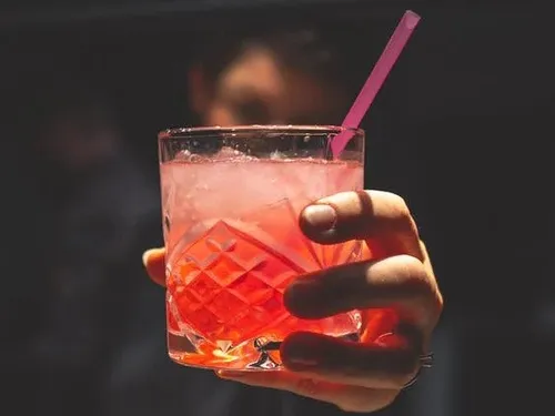 A glass of drink is held by one hand.