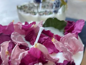 Candle with colorful petals is lying on a table.