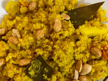 Yellow dish with grains, nuts and spices.