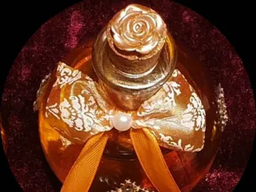 A perfume bottle with a decorative bow and rose.