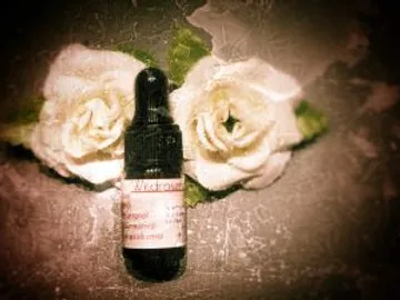 A bottle lies between two white roses on a surface.
